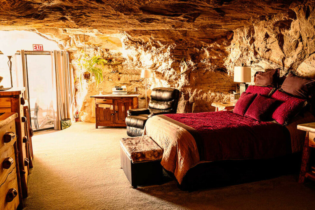 En säng med rött överkast i en grotta