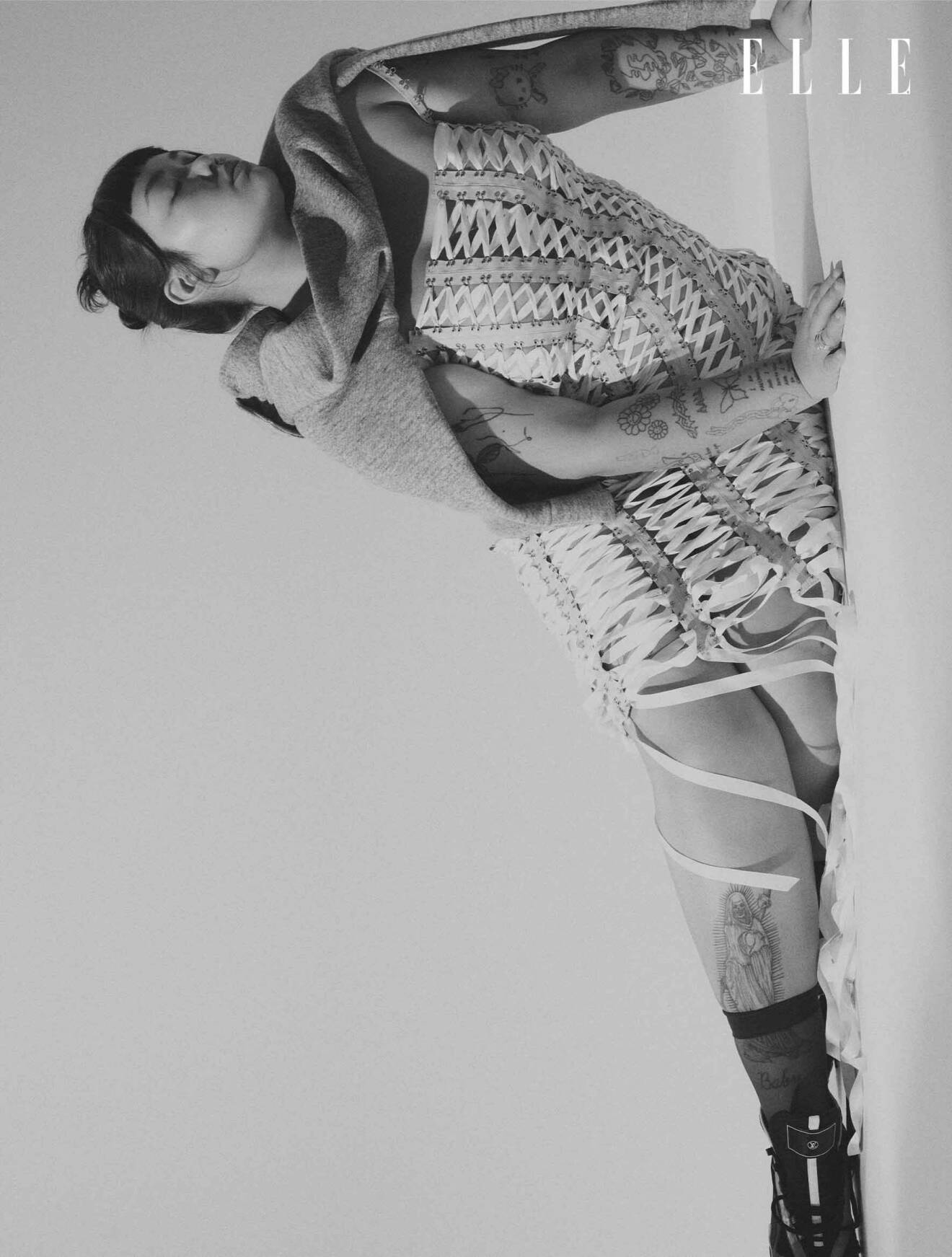 Modellen bär en klänning med snörning från Freja Wesik, med en grå sweatshirt över axlarna, från Teurn Studios