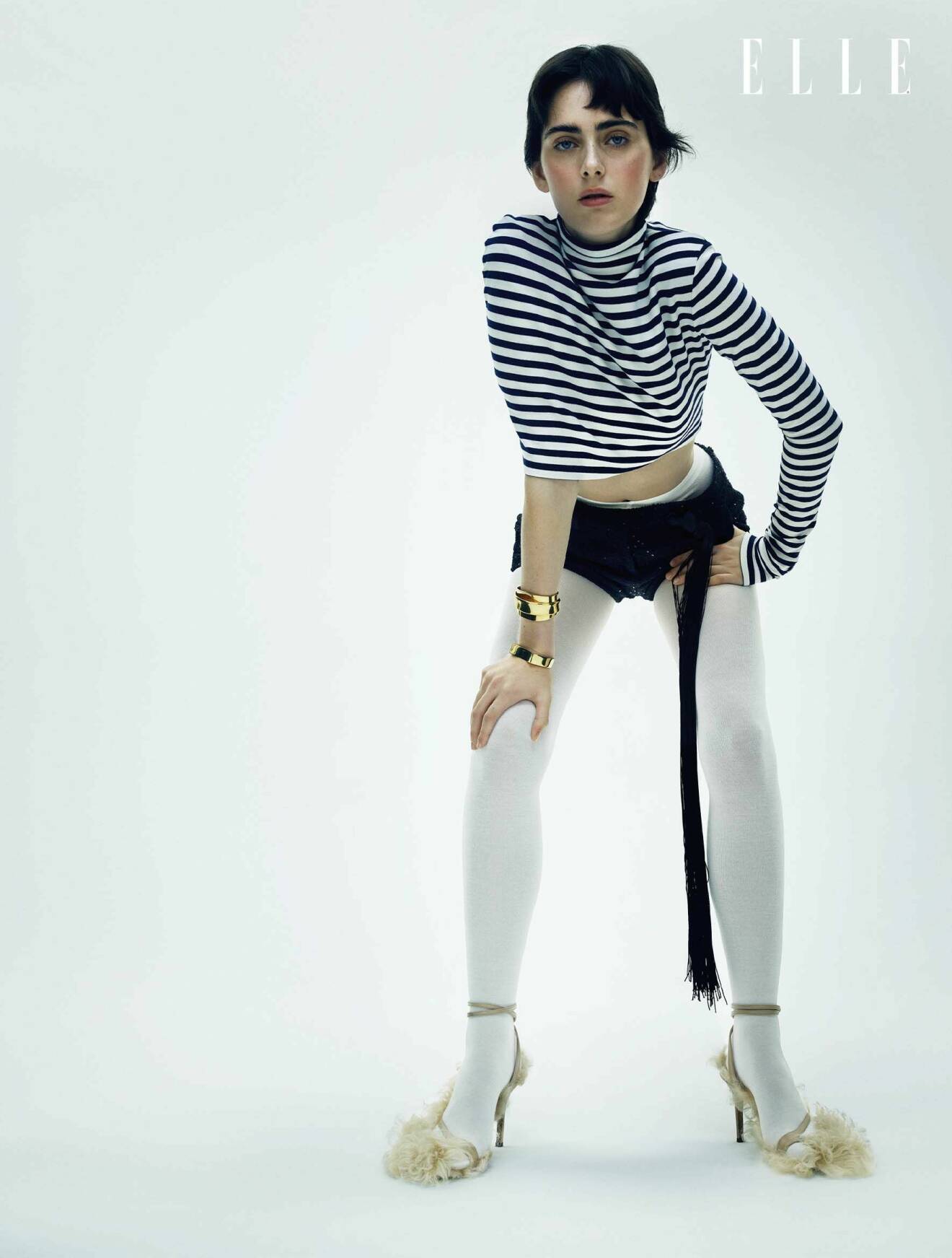 Modellen har på sig en randig tröja från Loewe, svarta shorts från Miu Miu och vita strumpbyxor från Wolford