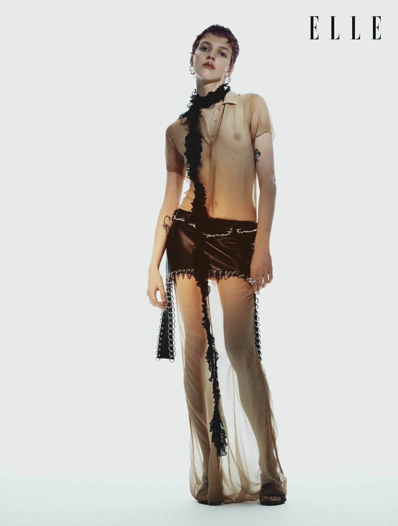 Modellen bär en skir långklänning med en kort brun kjol över