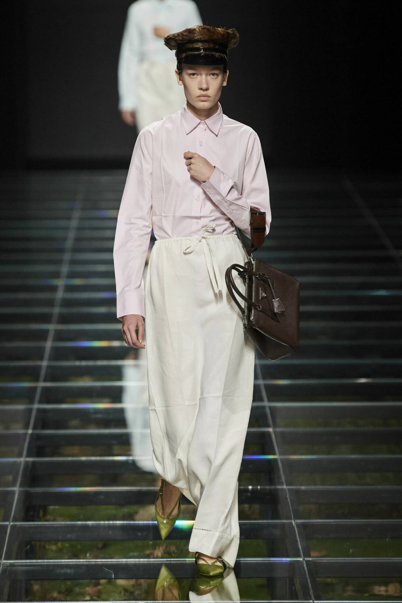 Prada AW24 look med rosa skjorta och vit kjol och brun väska.