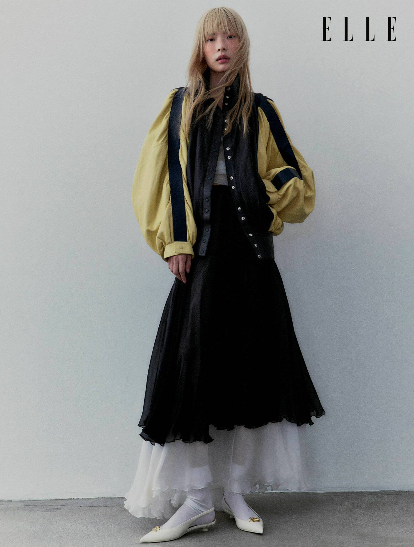 Modellen har på sig en svart kjol och jacka med gula ärmar från Louis Vuitton