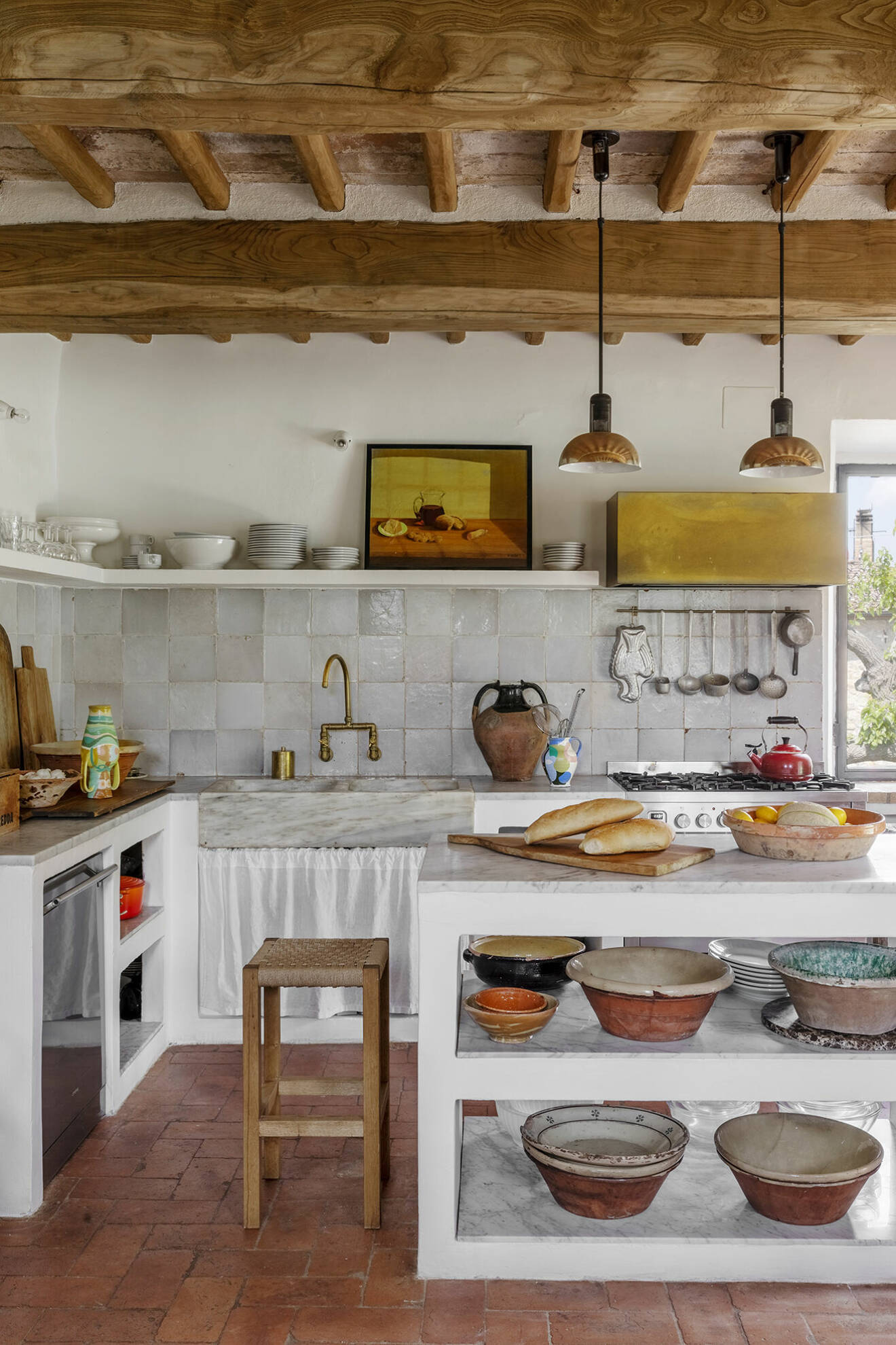 Rustikt och unikt. Köket har typiska toskanska terrakottagolv, de omålade träbjälkarna ger rummet en varm känsla. Liselottes samling av keramikskålar under den öppna köksbänken.