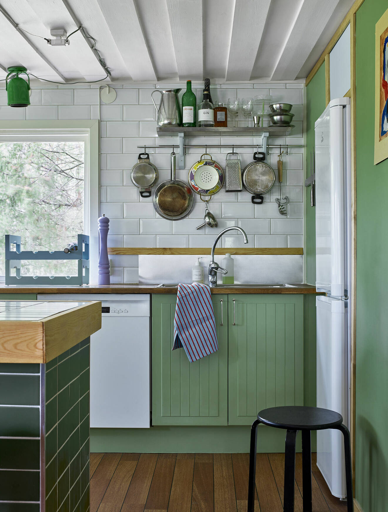 Med vitt kakel, grön färg och en hemsnickrad köksö blev köket som nytt. Den gröna taklampan som anas är egentligen en sänglampa från 70-talet.