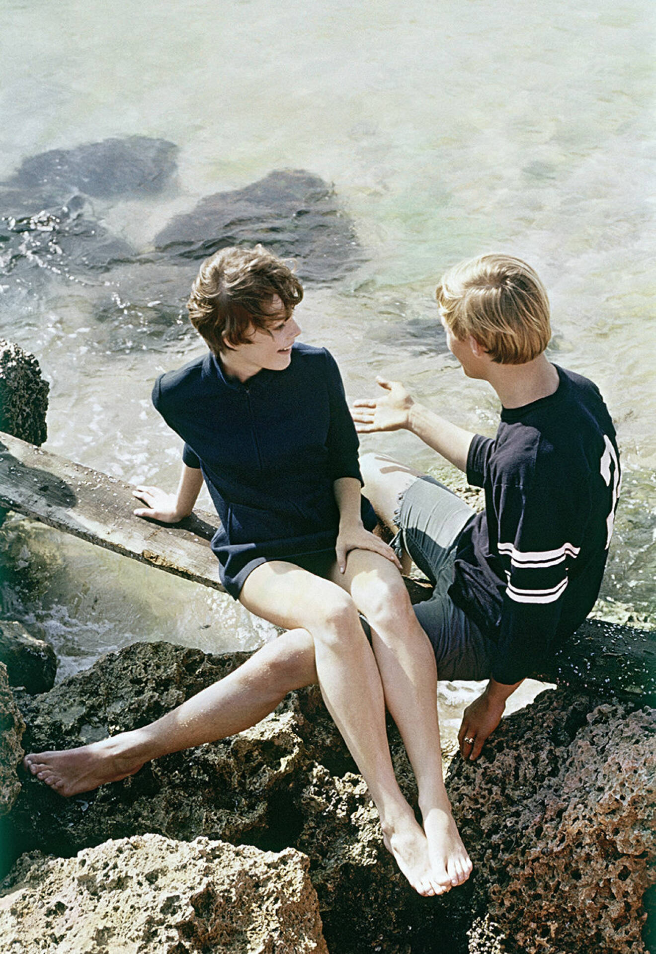 Couple Sits on Rocky Shore