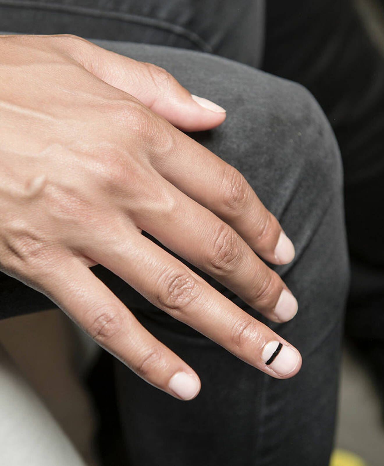 Vita naglar, en av de lackade med ett svart streck tvärsöver nageln