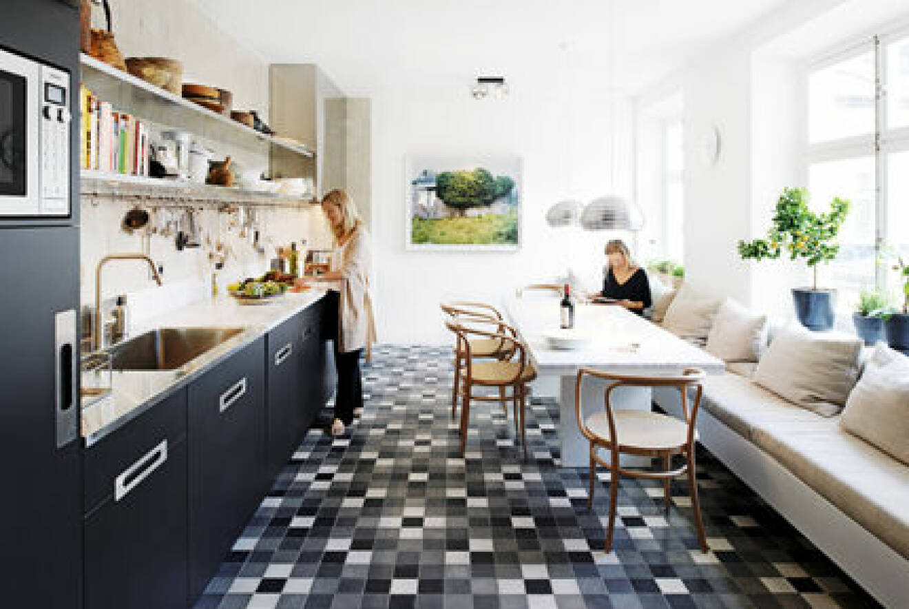Kök med svarta luckor och ett mönstrat golv. Köket inklusive marmorbordet är ritat av Björn Aaro.