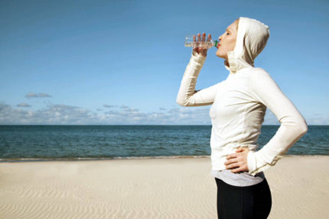 Female exercising and drinking water from bottle on Australian Beach