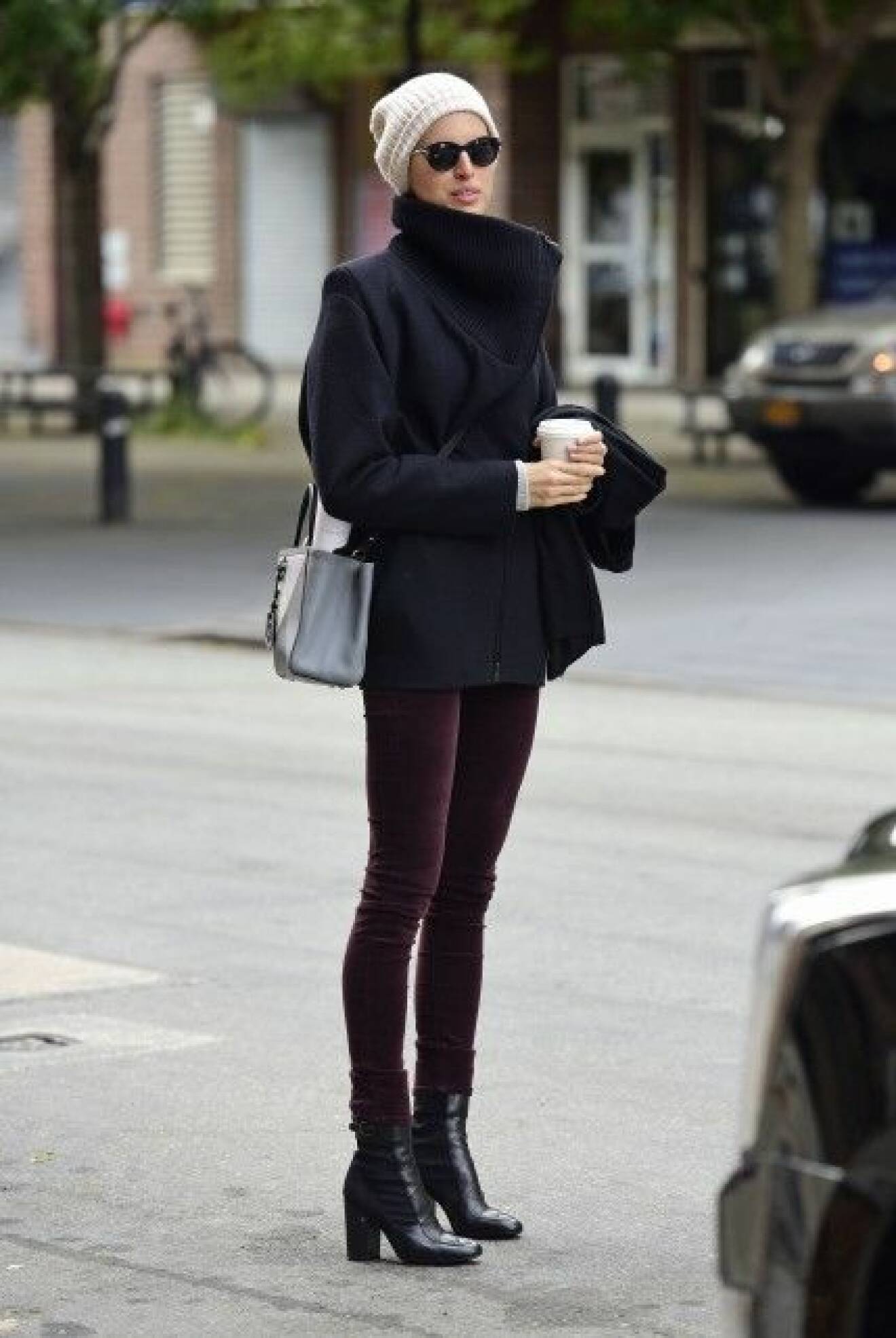 Karolina Kurkova texts and holds her coffee while waiting for a cab in Tribeca in NYC