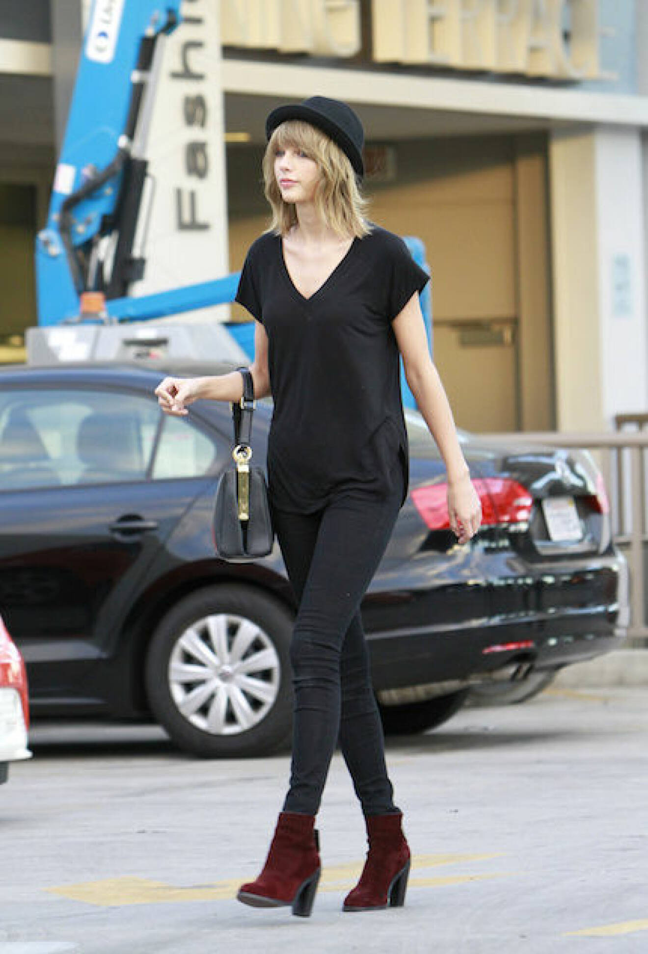 EXCLUSIVE: Taylor Swift pairs a bowler hat with an all black ensemble as she parades down the street carrying her designer purse while flanked by her two private security guards