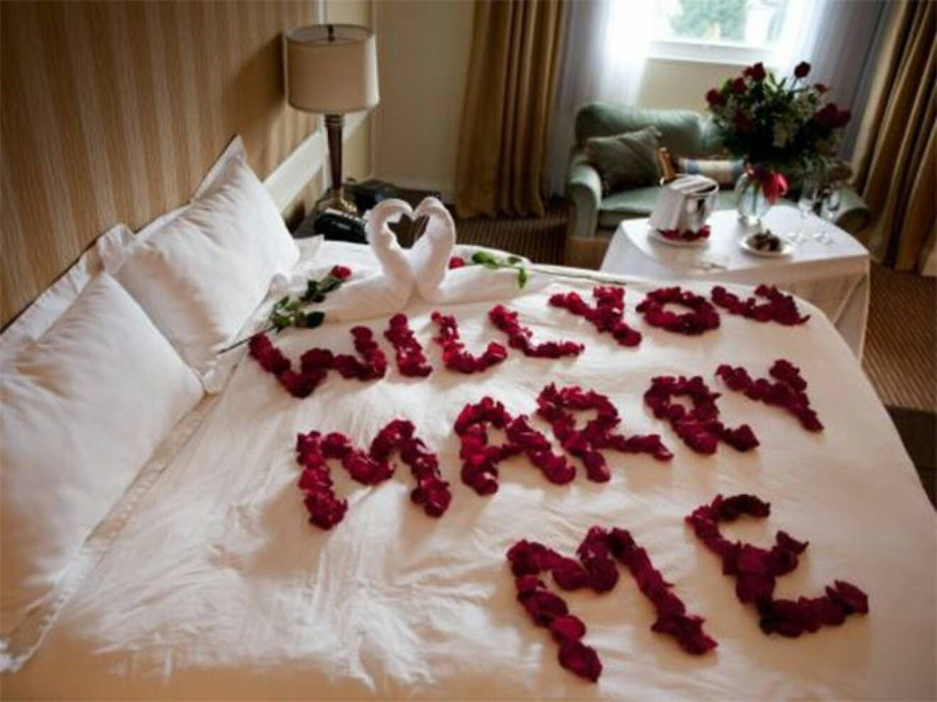 Säng dekorerad med rosblad i texten "Will you marry me?"