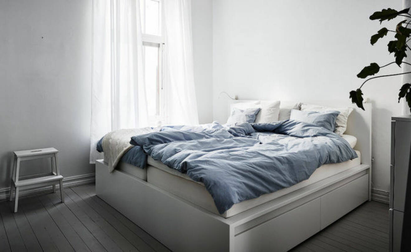 Ljust sovrum med stor säng och vita gardiner.