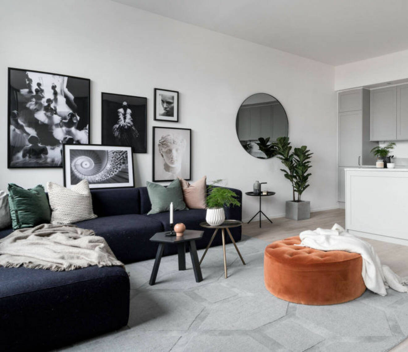Ljust vardagsrum bryts av med svart soffa med färgglada kuddar