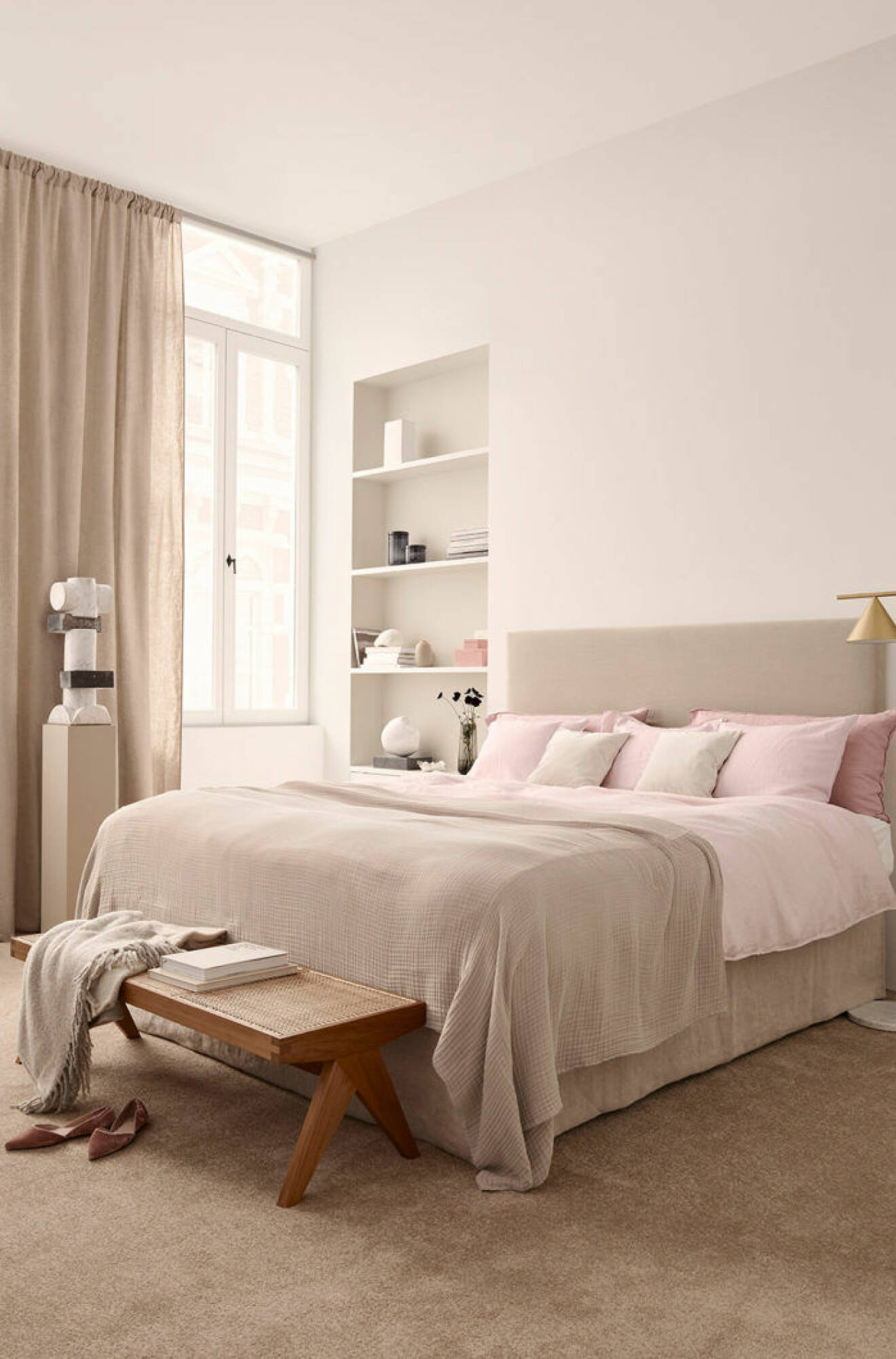 Sovrum i beige med rosa sängkläder, sänglampa i mässing och piedestal. H&M Home våren 2018.