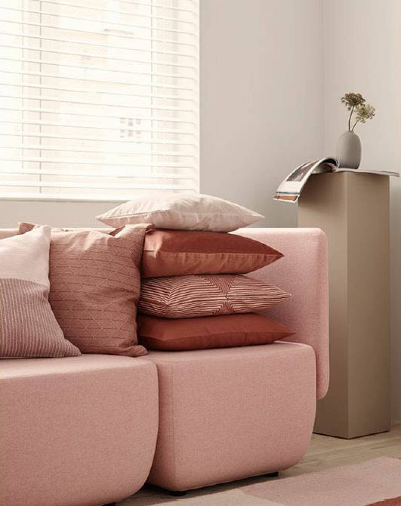 Rosa soffa, rosa pydnadskuddar, beige piedestal med vas på. H&M Home för våren 2018. 