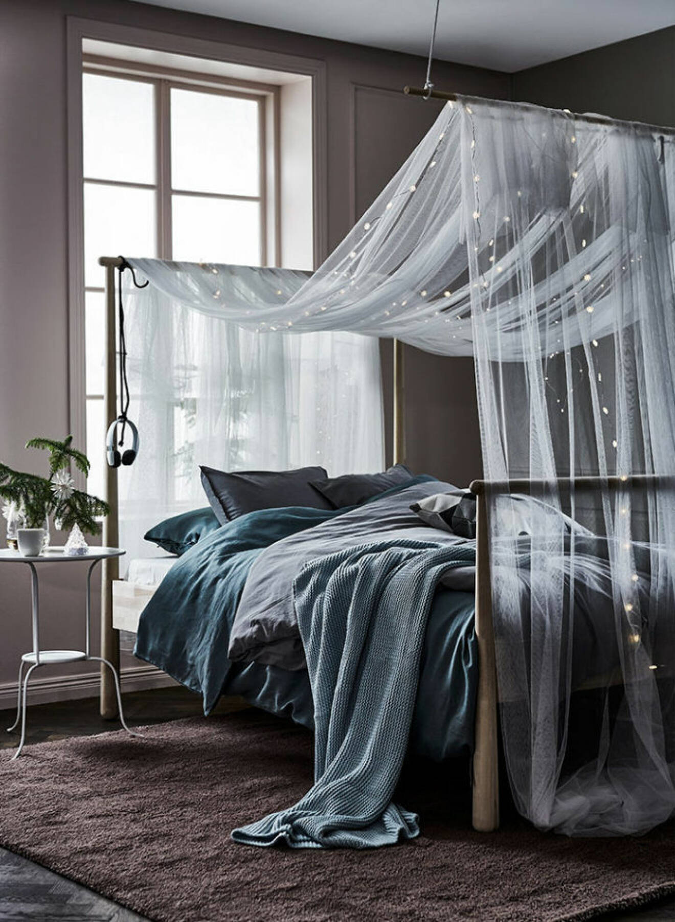 Ljusgråa sängkläder möter fin sänghimmel med lampor