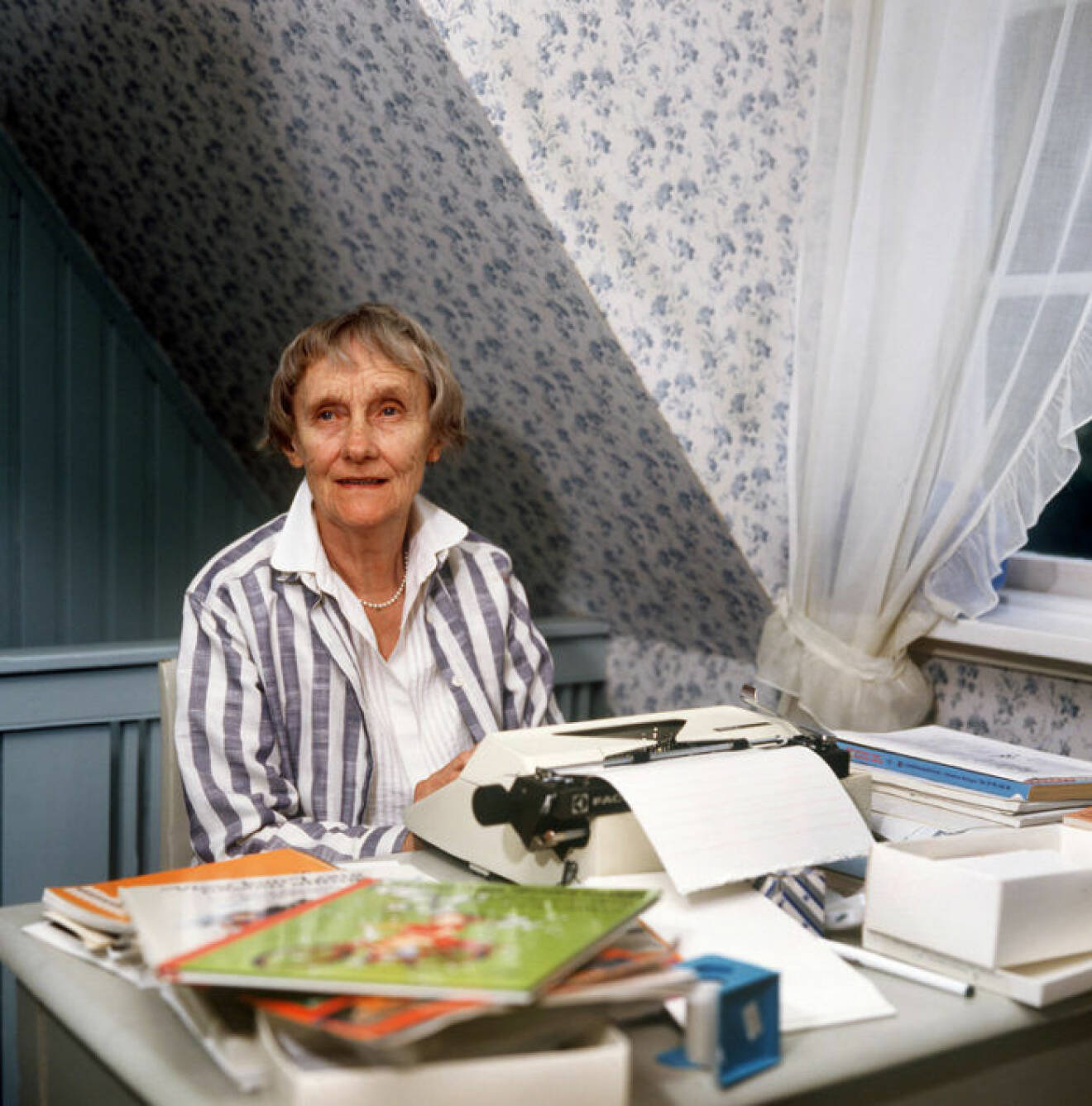 Astrid Lindgren sitter bakom en skrivmaskin 1987. Framför henne ligger böcker om Pippi Långstrump.
