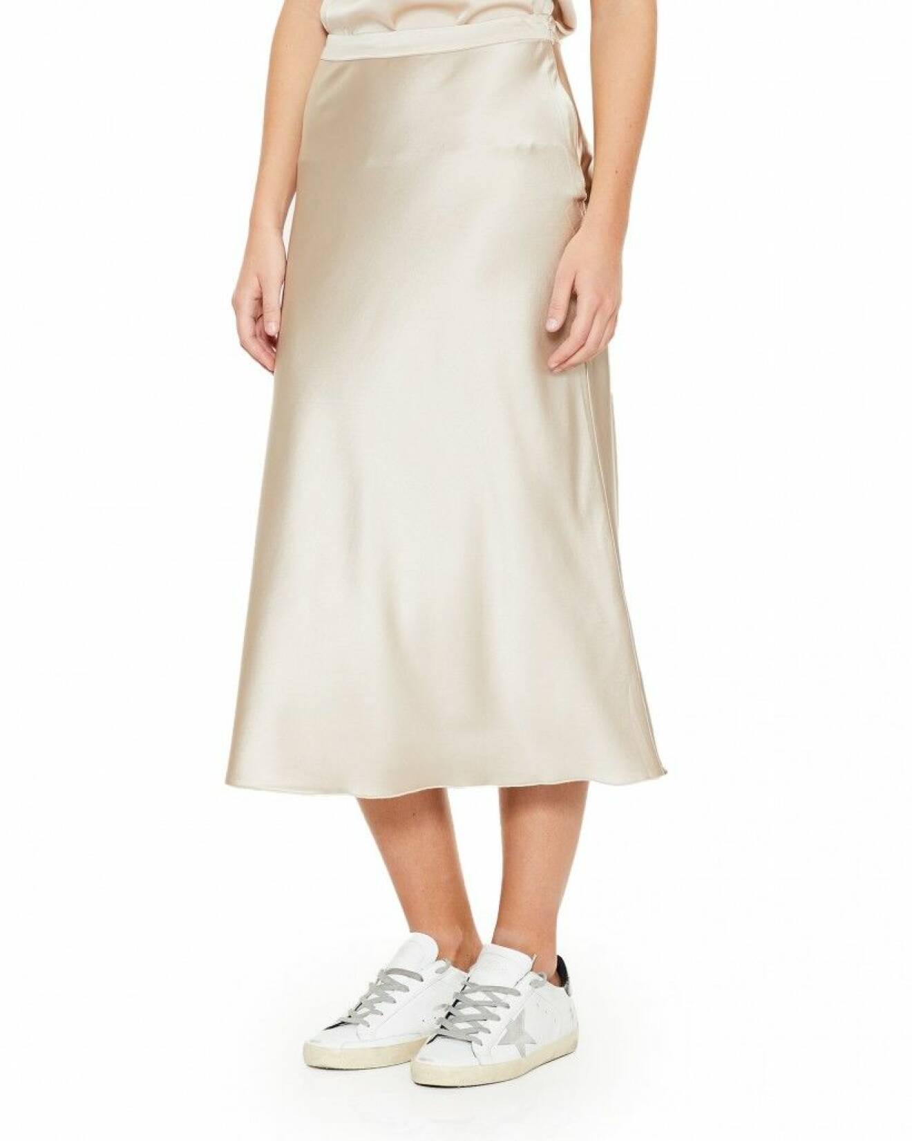 Klä dig i beige siden när du vill addera en känsla av lyx och bär den tillsammans med en vit bomullsskjorta. En perfekt matchning. Sidenkjol från Ahlvar Gallery.