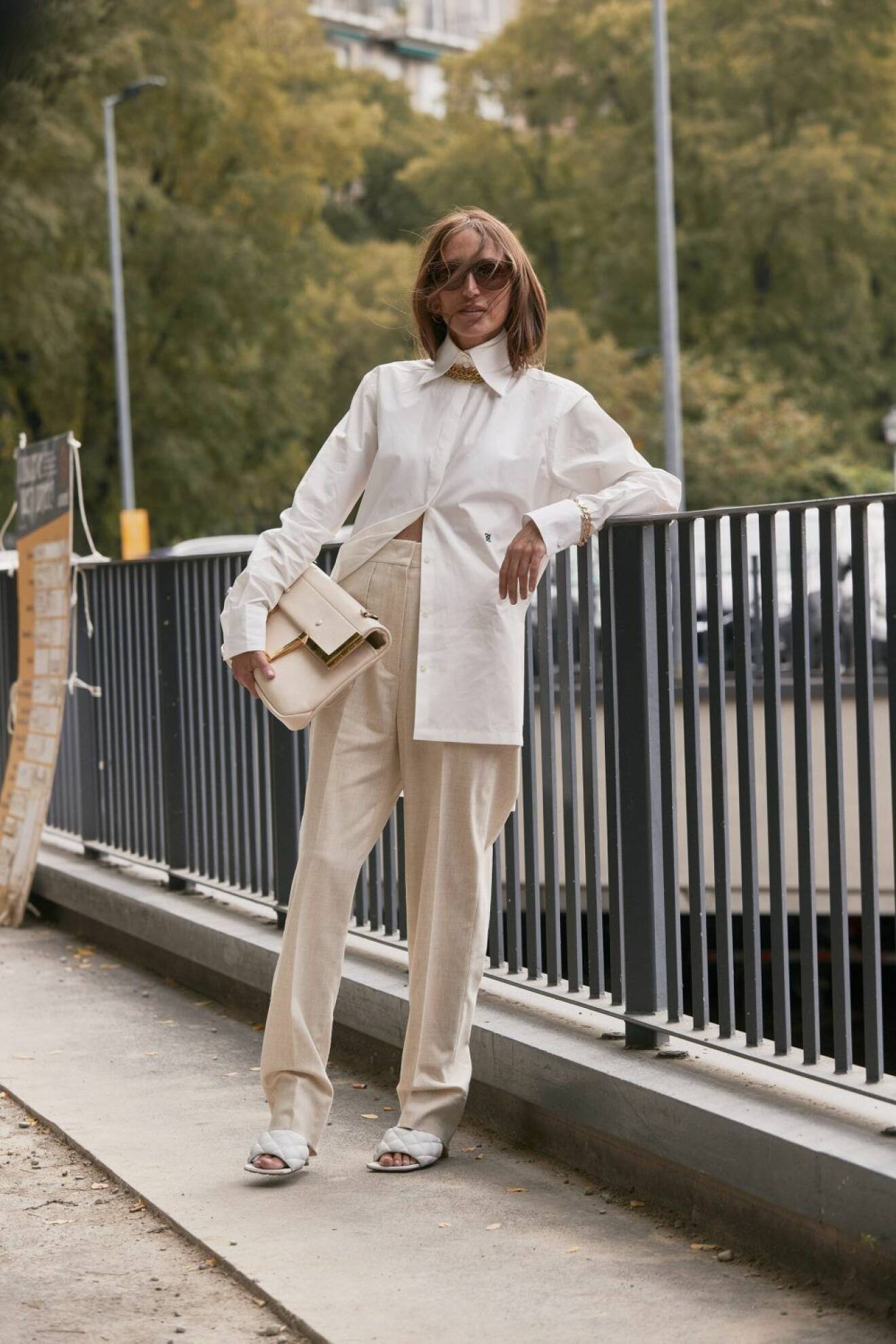 Milano Fashion Week Streetstyle SS20. Kvinna i vit skjorta och beigea byxor.