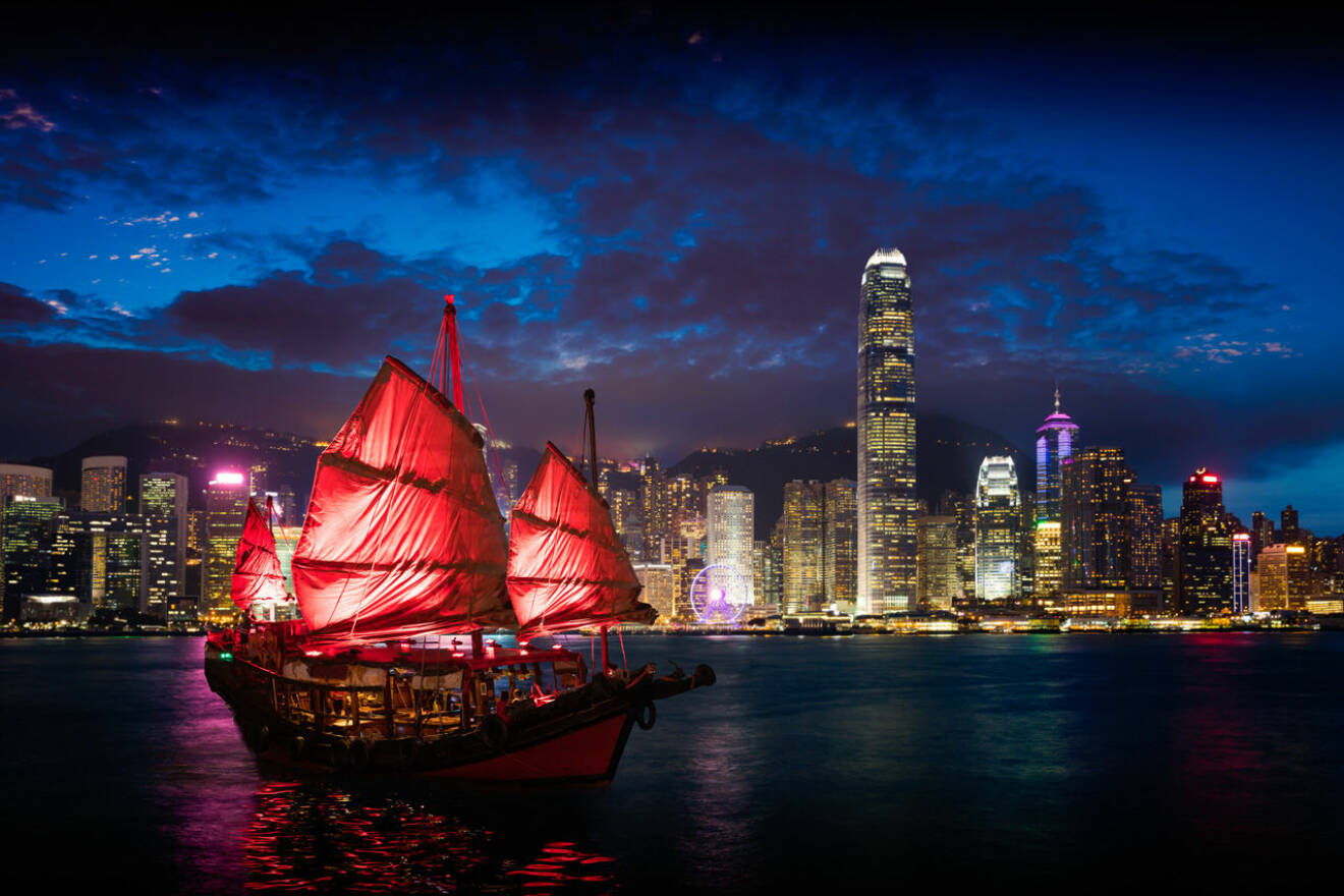 Hong Kong på kvällen med asiatisk röd båt