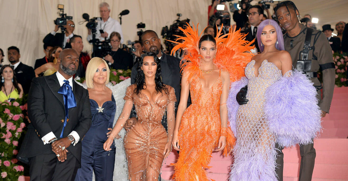 Familjen Kardashian/Jenner står i en trapp och blir fotade av massa paparazzifotografer