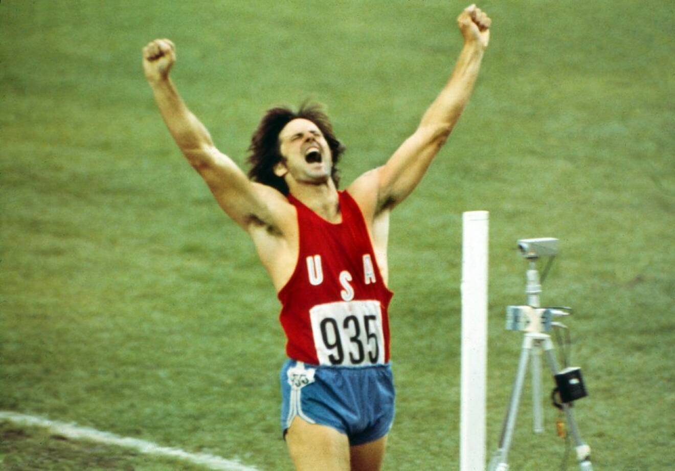 Bruce Jenner sträcker upp armarna i luften och skriker av glädje när han vinner OS-guld