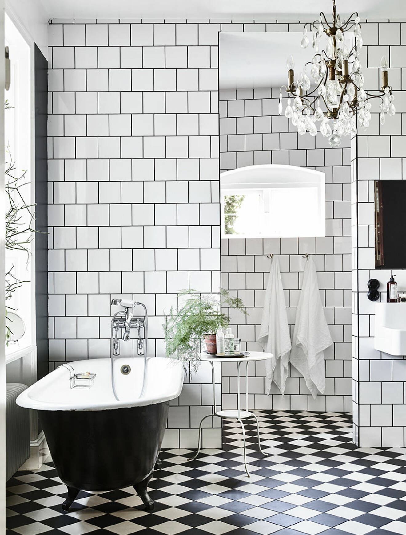 Svart badkar i badrum med vit och svart-rutigt klinkergolv