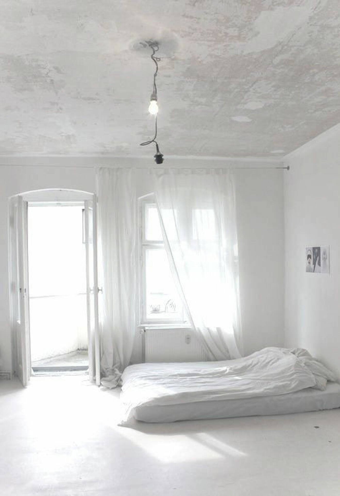 Ett vitt sovrum med sängen på golvet