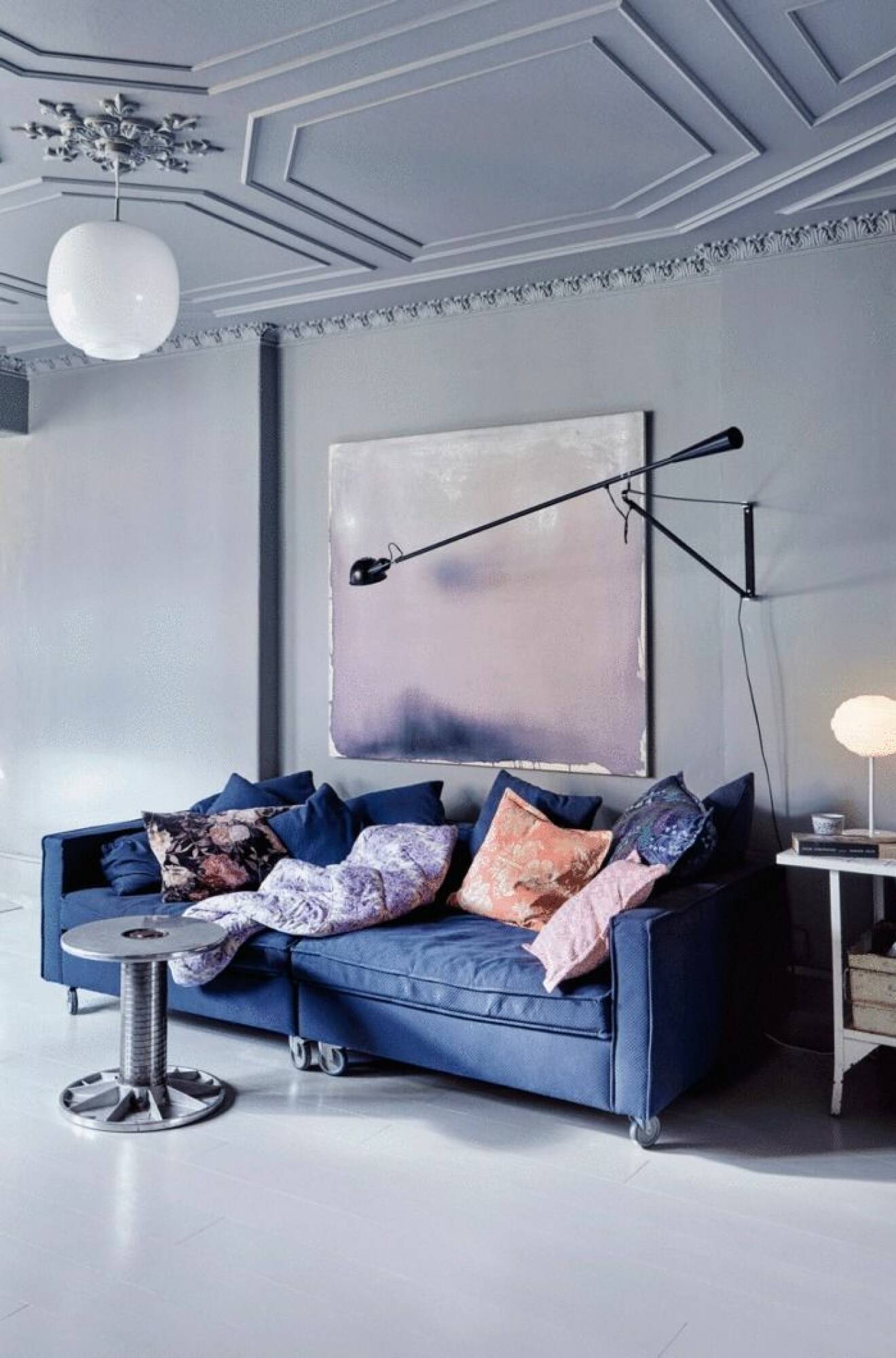 Blå soffa blir en bra kontrast i det gråmålade hemmet