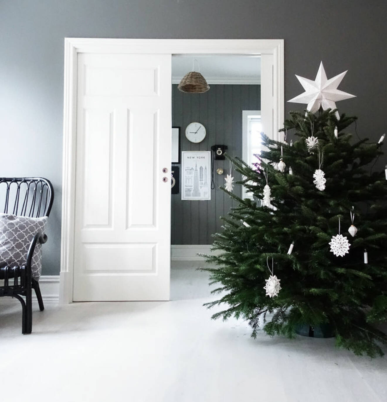 Bryt av ett gråmålat rum med en stor, vacker julgran