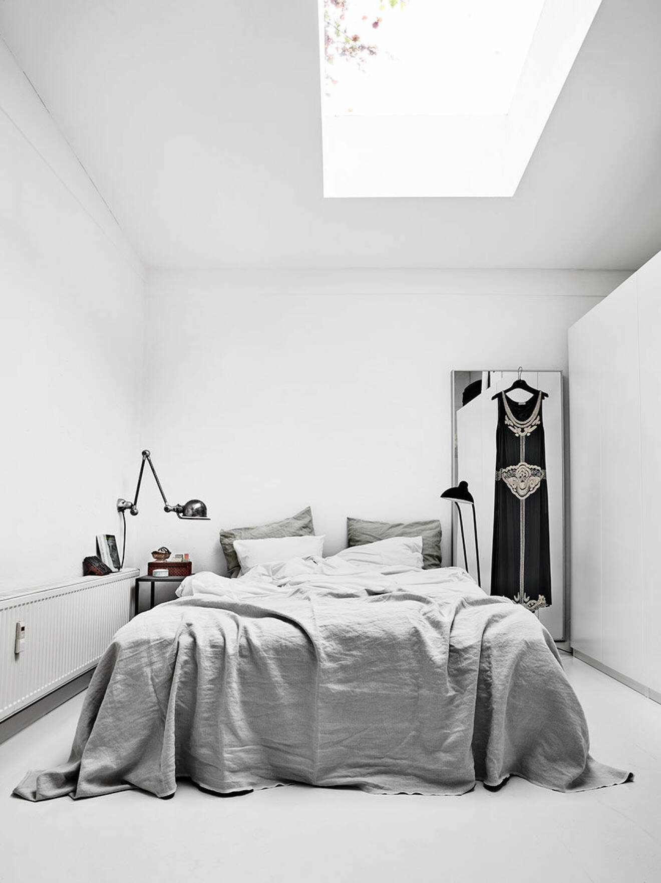 Från sängen  i det ljusa sovrummet  kan paret somna  till regnets trummande  på takfönstret.  Sängkläderna är  hemsydda av tyg från  belgiska Libeco.  Vintagelampa från  Jieldé och golvlampa  från Christian Dell.