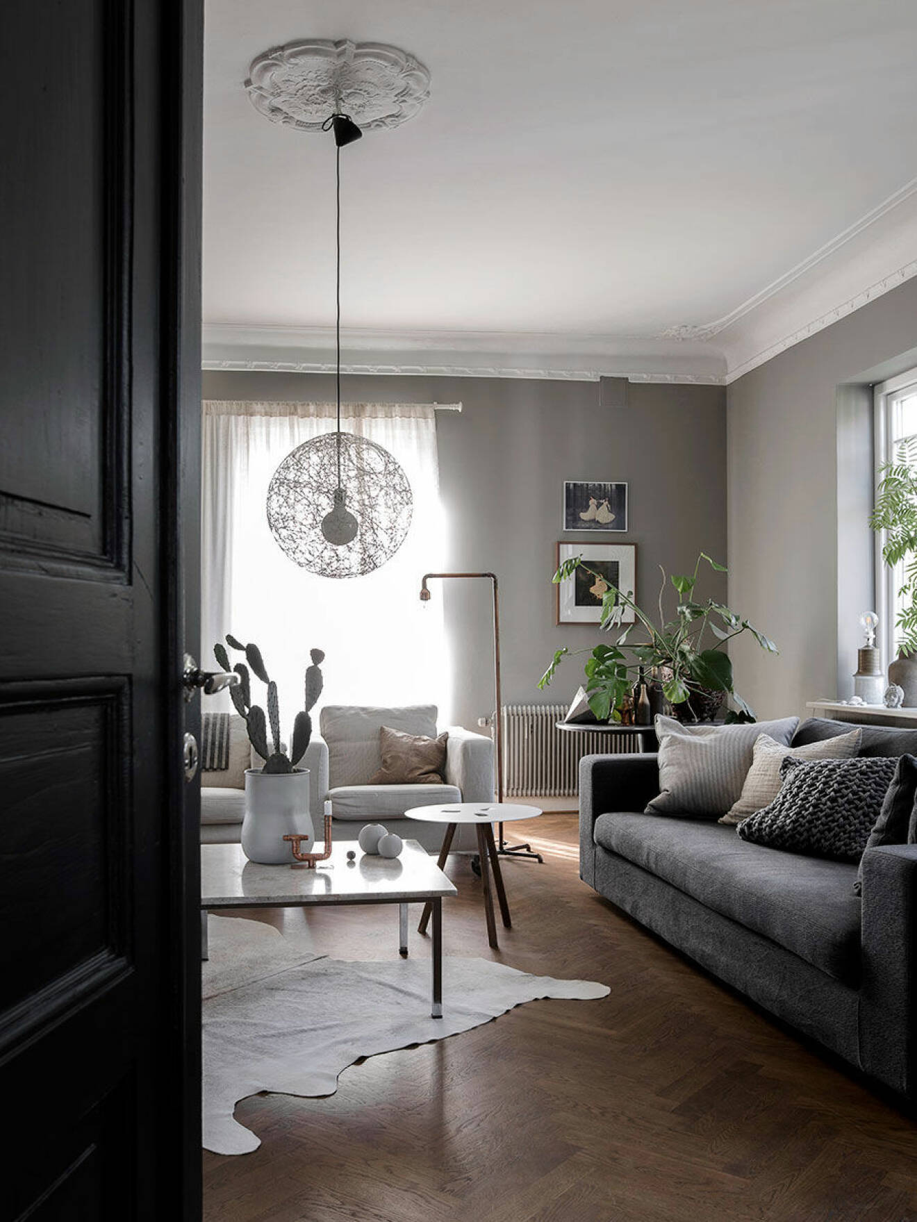 Vardagsrum med gråa väggar, grå soffa, vit matta