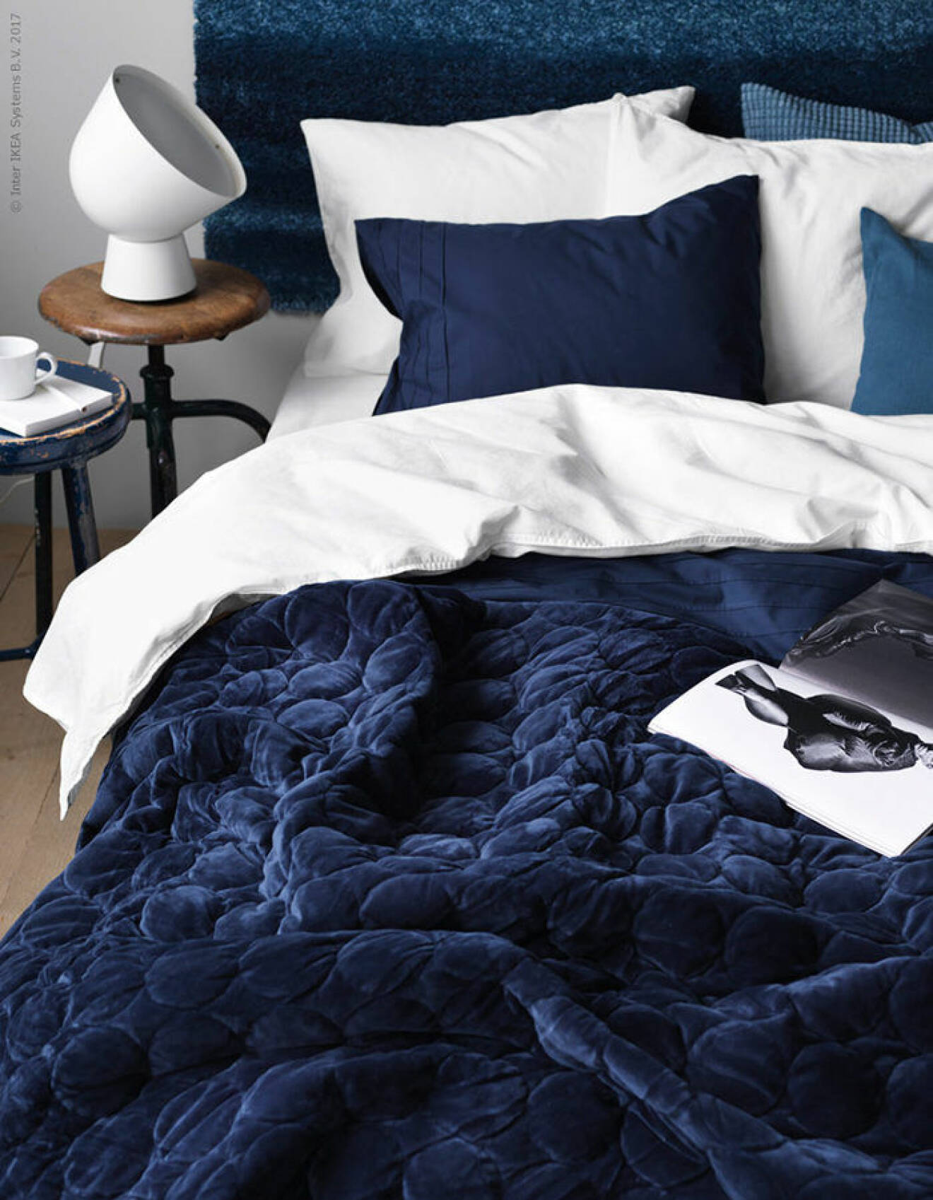 Säng med blått överkast, blåa kuddar och blå sänggavel
