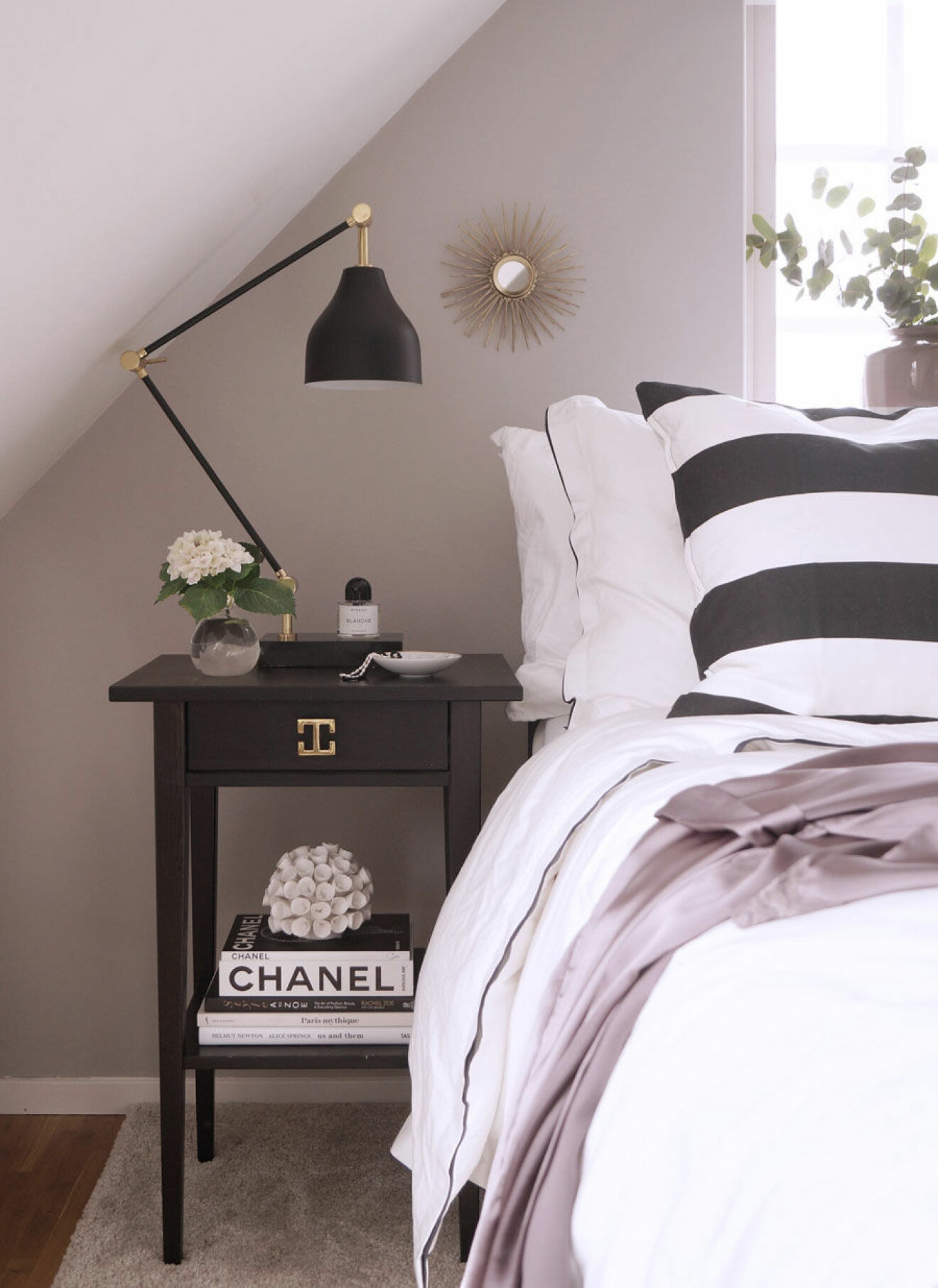 Sovrum med svart och vitrandigt örngott, naturrosa väggfärg