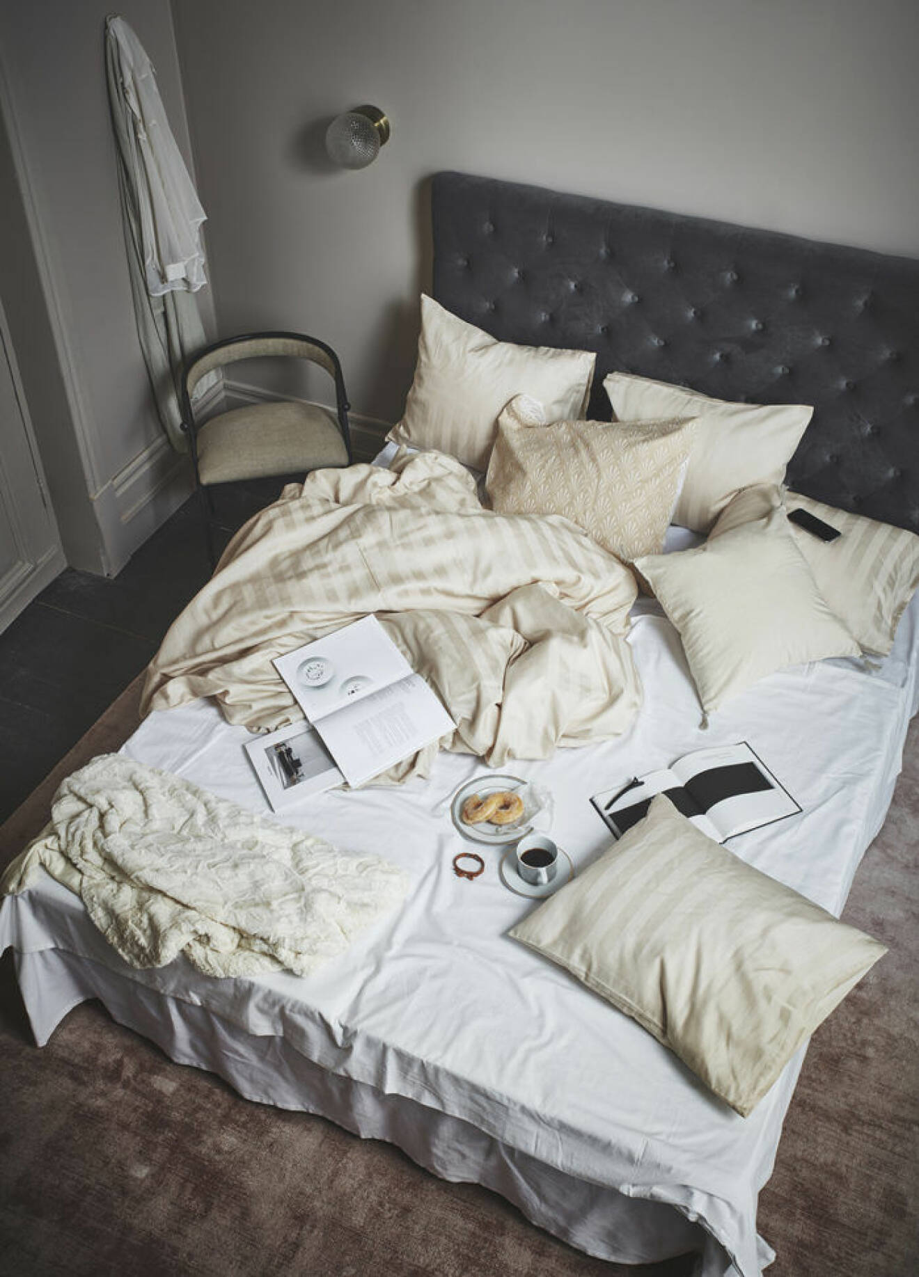 Sovrum med stoppad sänggavel i sammet och beige sängkläder. Slarvig bäddning. Jotex våren 2018.