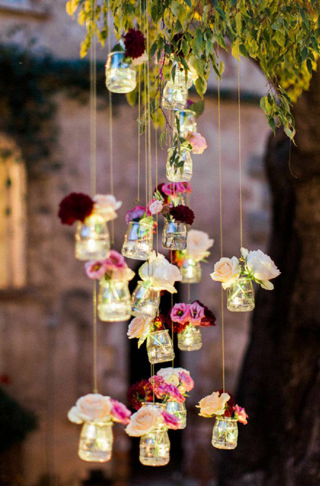 Glasburkar upphängda i träd, med blommor. Trädgårdsbröllop. 
