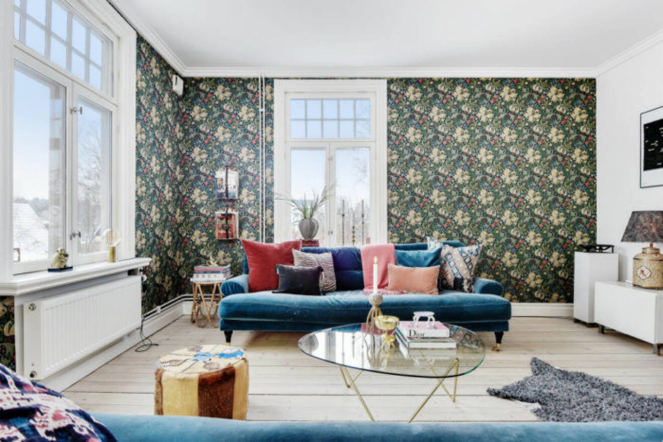 Vardagsrummet med tapetserade väggar och blå soffa i sammet