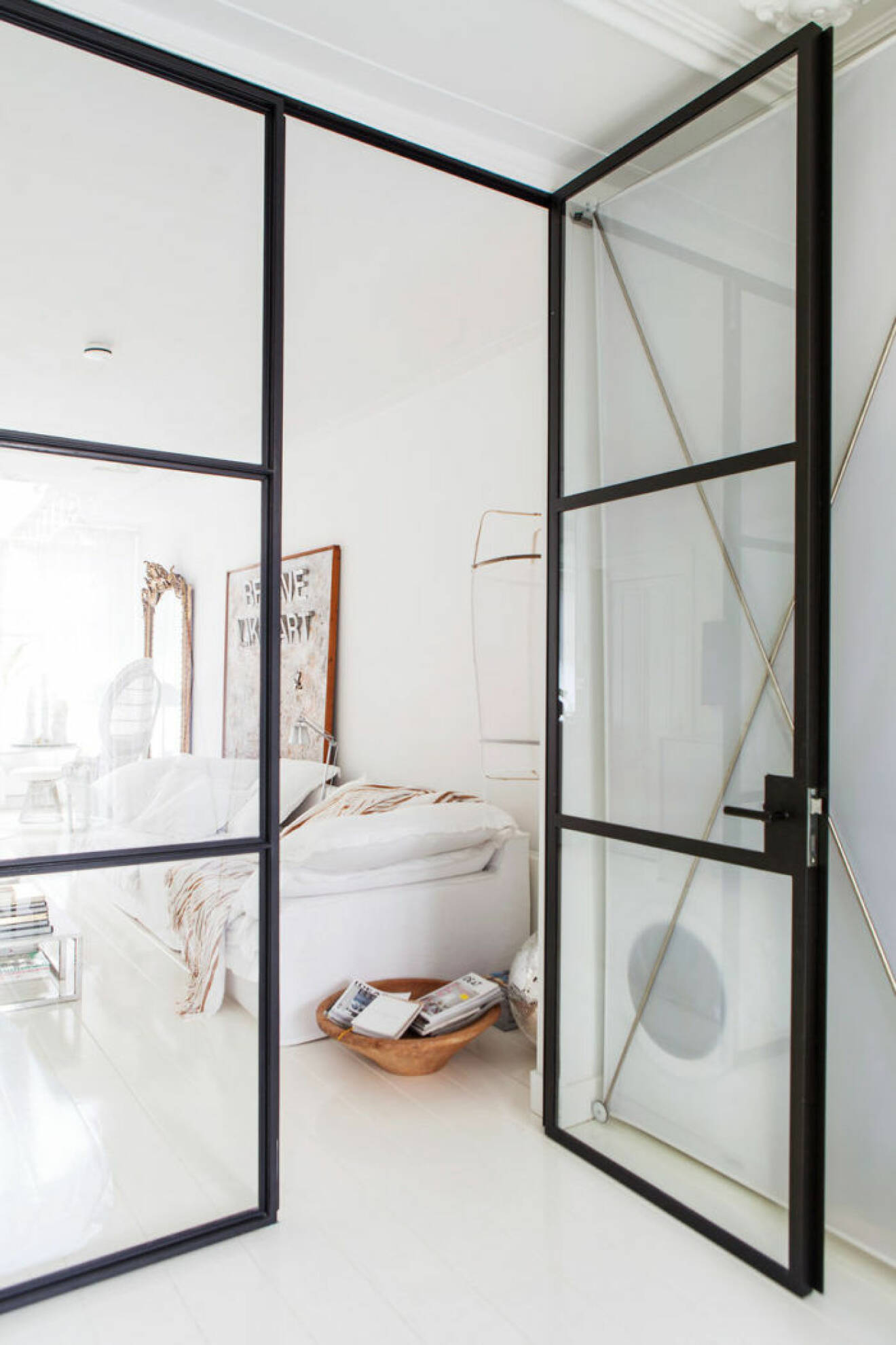 En glasvägg i industristil skärmar av på ett snyggt sätt i compact living-lägenheten.
