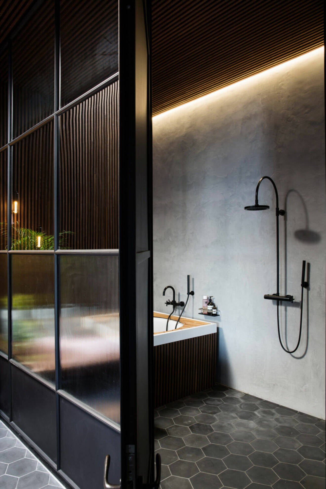 Stort badrum med skiljevägg med frostade glas och olika nyanser av svart