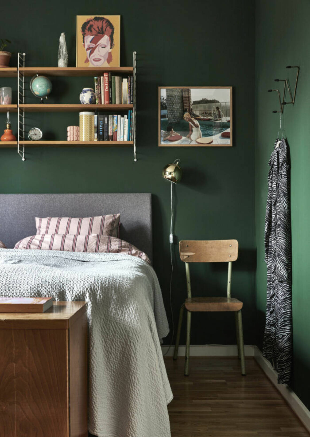 Det mörkgrönmålade sovrummet med väggfäst bokhylla