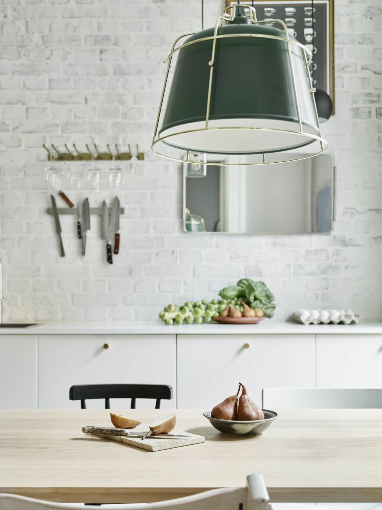 Vitmålat kök med grön belysning, träbord och spegel