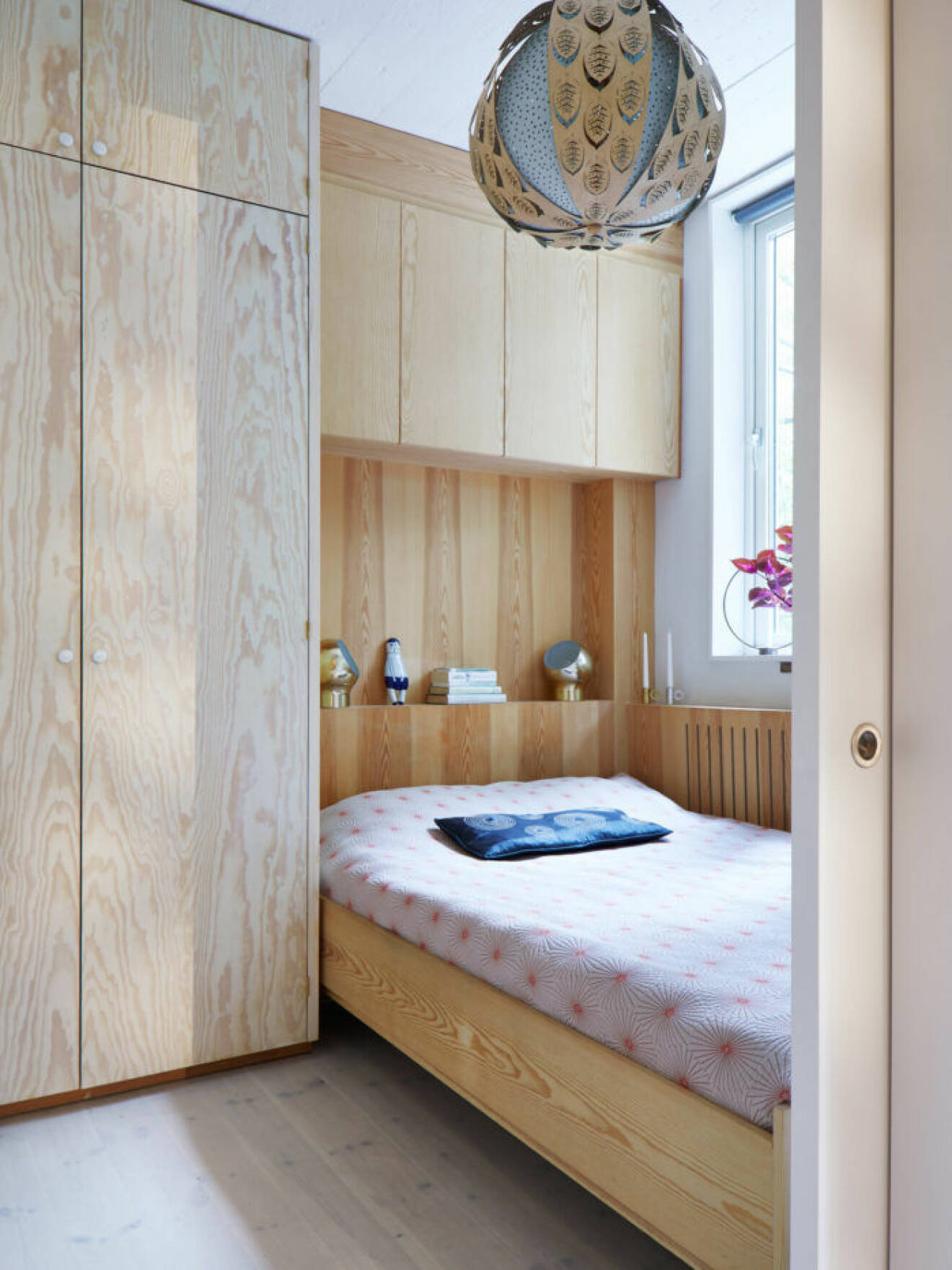Sovrummet går i ljust trä med platsbyggd förvaring både bredvid och över sängen