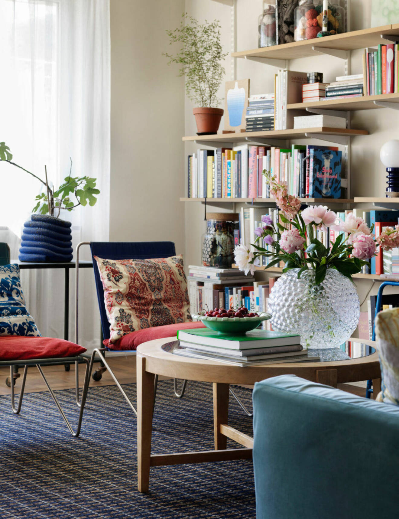 Färgglad lägenhet i Stockholm, runt träbord och bokhylla i samma träslag