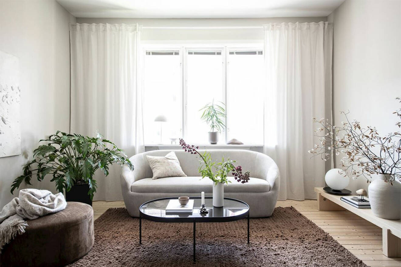 Vardagsrum med soffa och sittpuff i beige och brunt