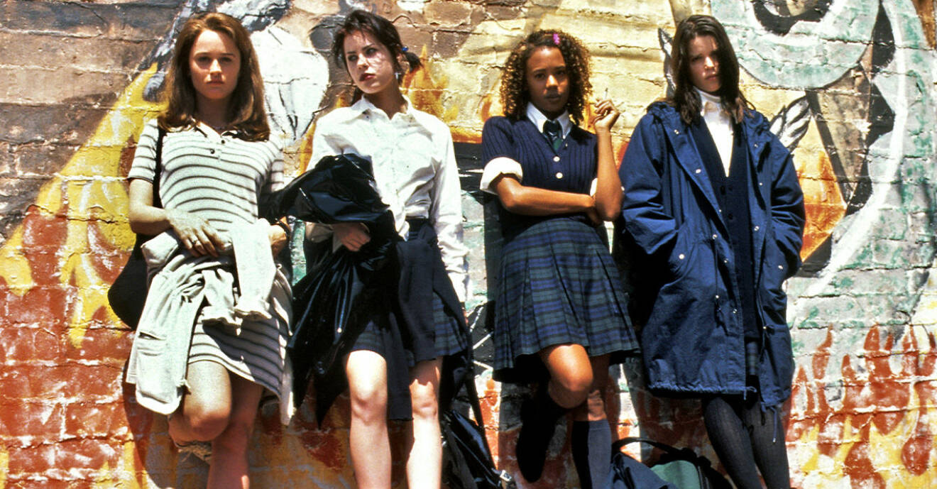 Tjejerna från kultfilmen The Craft 1996 uppradade mot en vägg i coola 90-tals kläder.