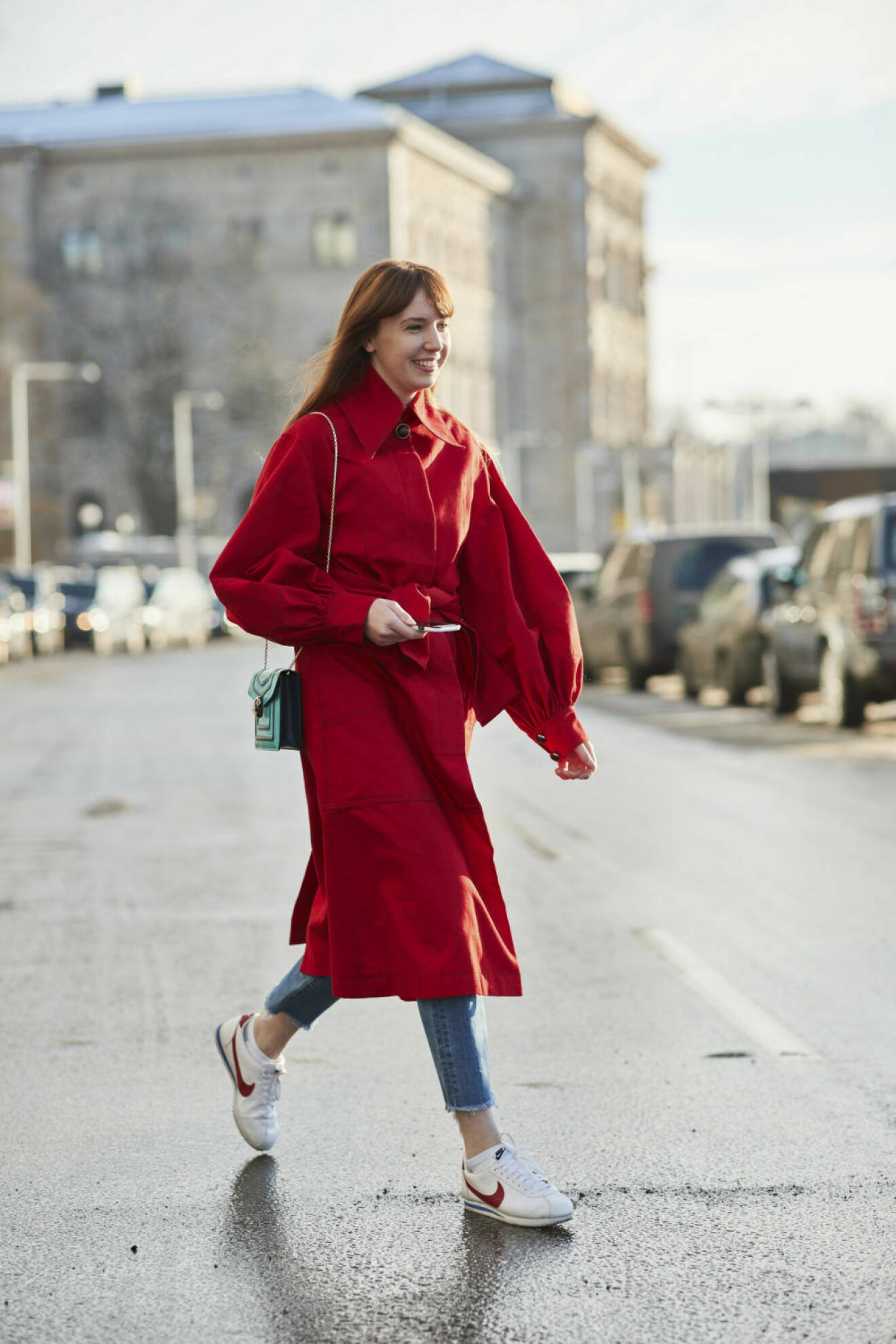 Närbild på kvinna i röd kappa med puffärmar och sneakers från Nike.
