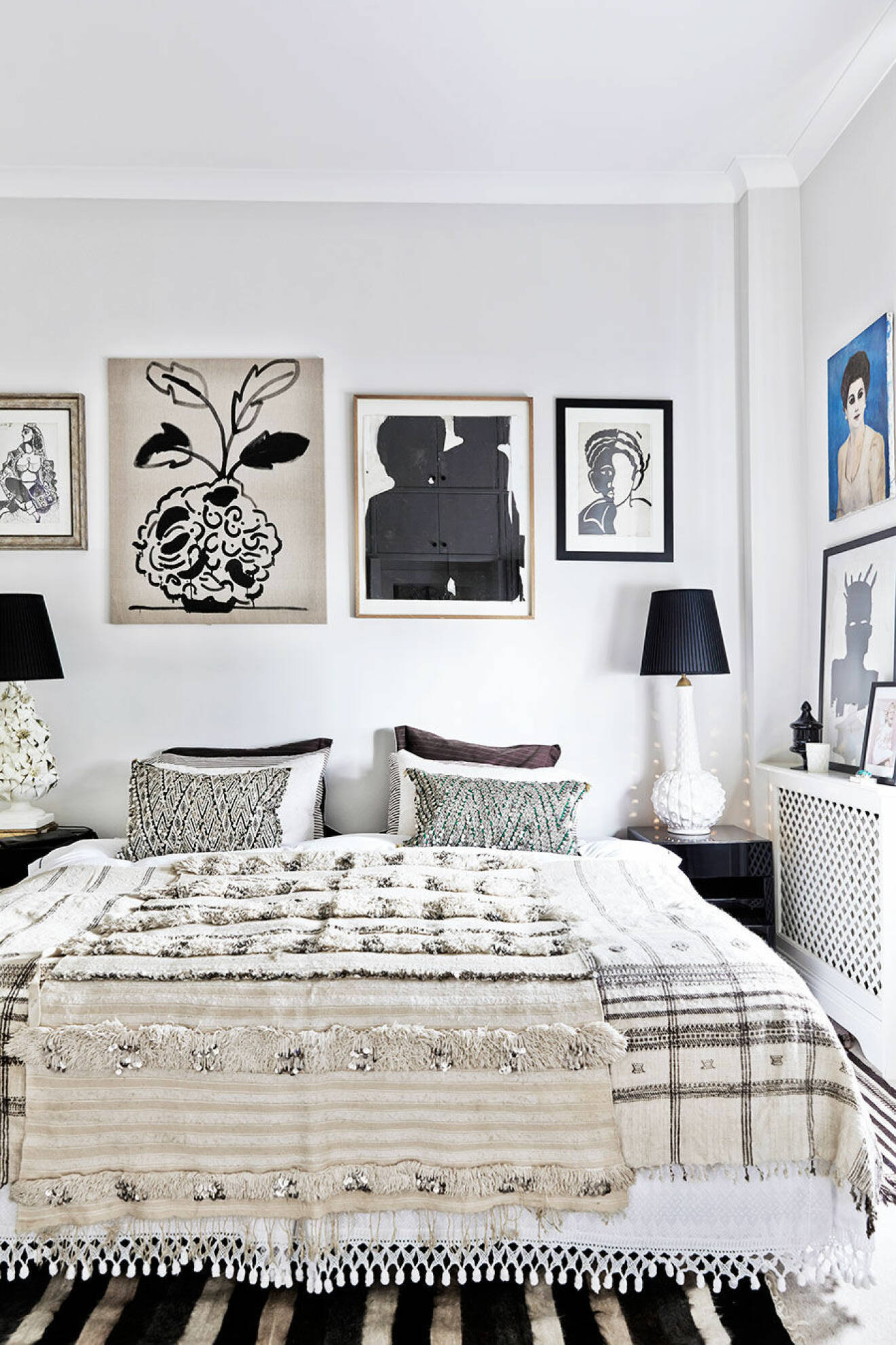 Inred med mönstrade sängkläder och geometriska konstverk på väggarna