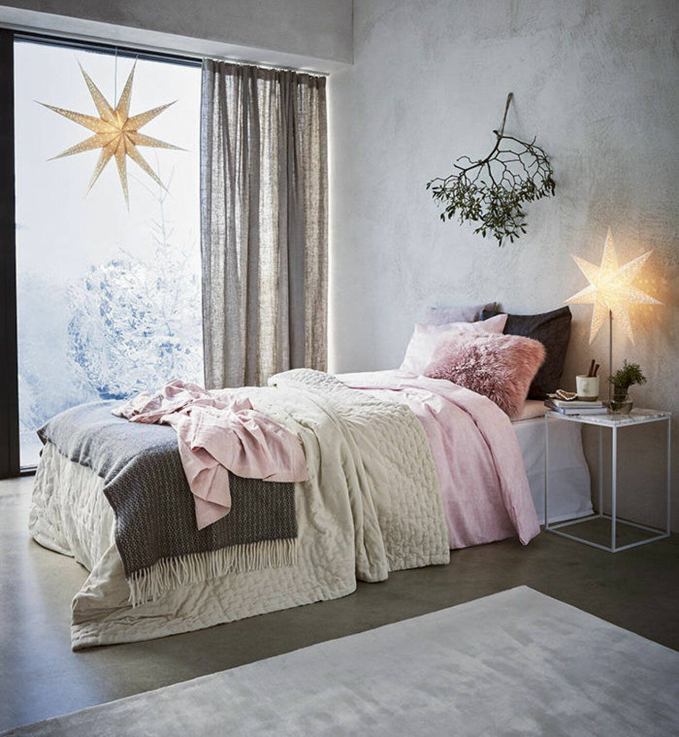 Sovrum med julstjärnor och vacker bäddning i rosa toner.