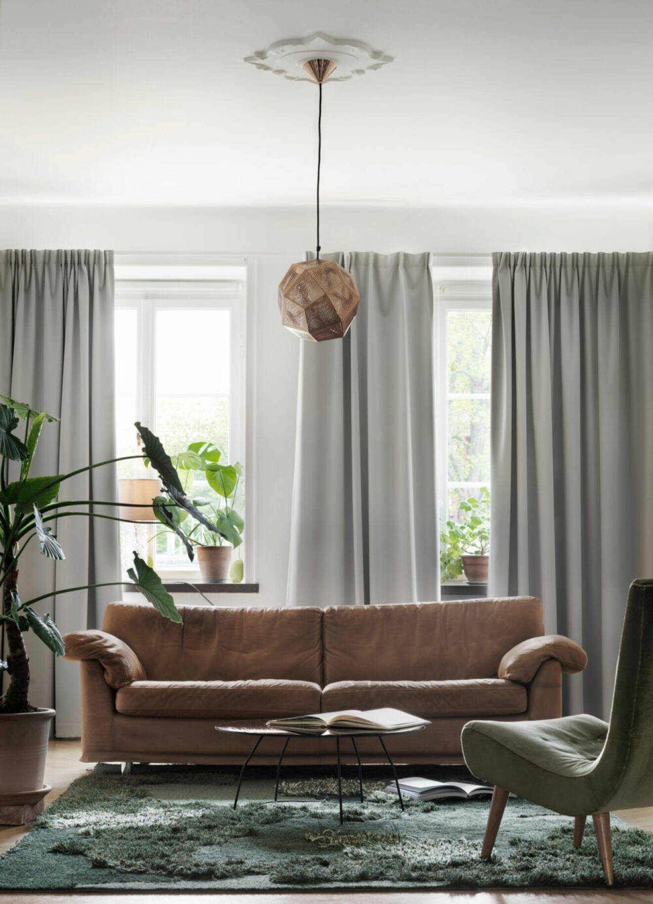 Brun soffa och gråa gardiner i lägenheten i Malmö