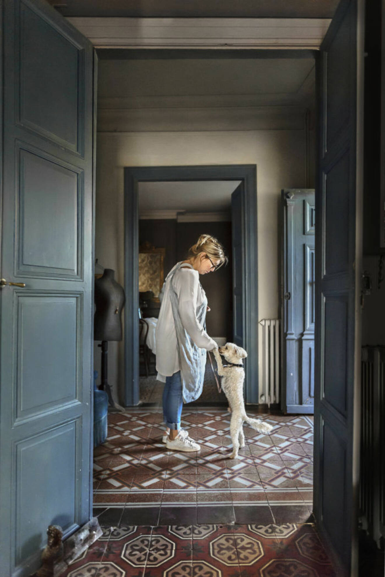 Mönstrat golv, kvinna med hund, blå dörr